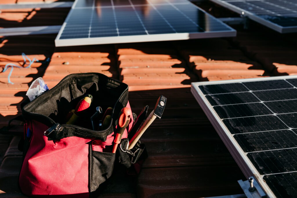 bag of technician tools and solar panel on roof during sunrise.Renewable energies
