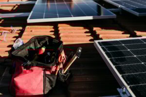 bag of technician tools and solar panel on roof during sunrise.Renewable energies